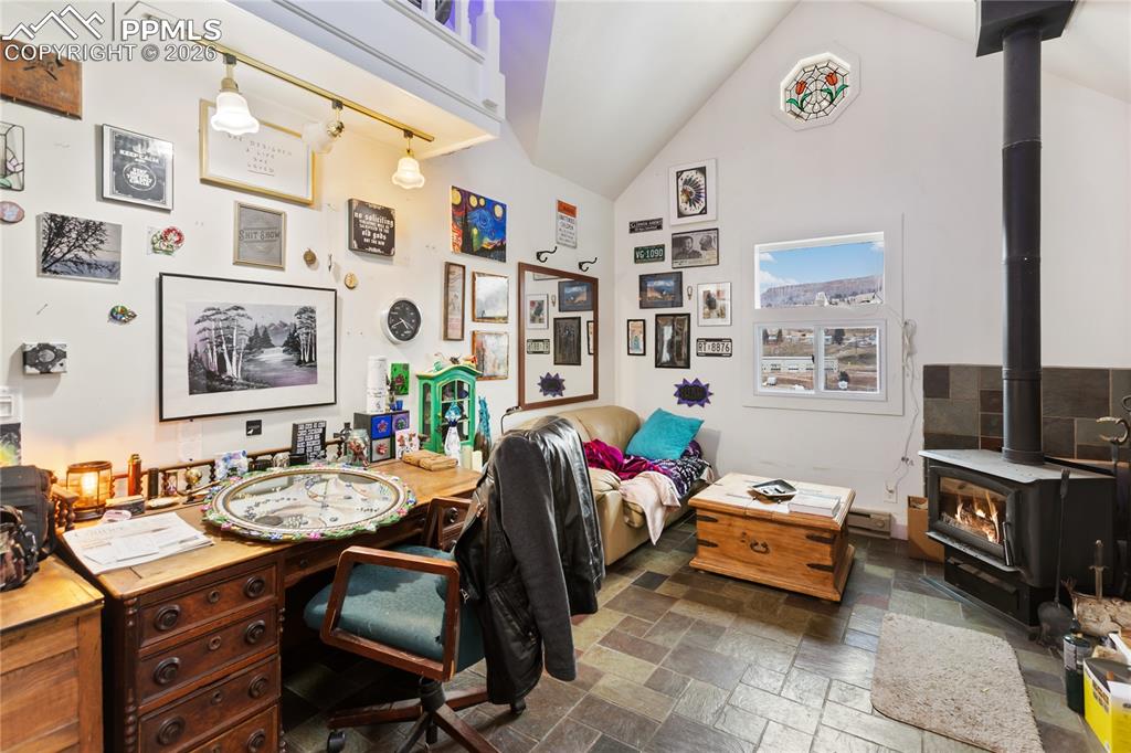 The living area has stone tile floors, a wood stove, lofted ceilings, and a stained-glass window!