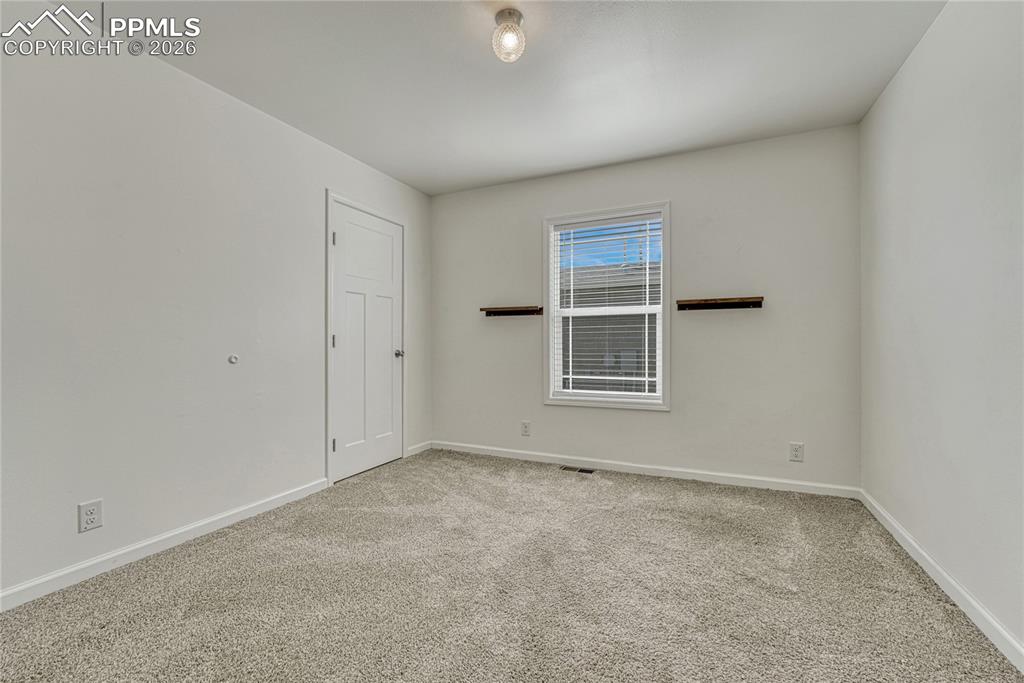 First bedroom just off the living room with carpeted floors, vinyl windows, and walk-in closet
