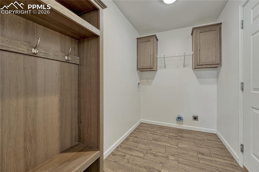 Laundry room with electric hook-ups, storage cabinets, entryway bench with coat rack, and access to the garage
