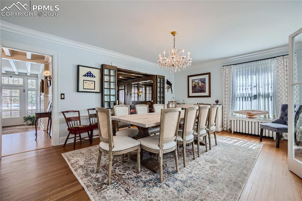 Dining room featuring hardwood / wood-style floors, ornamental molding, and a chandelier