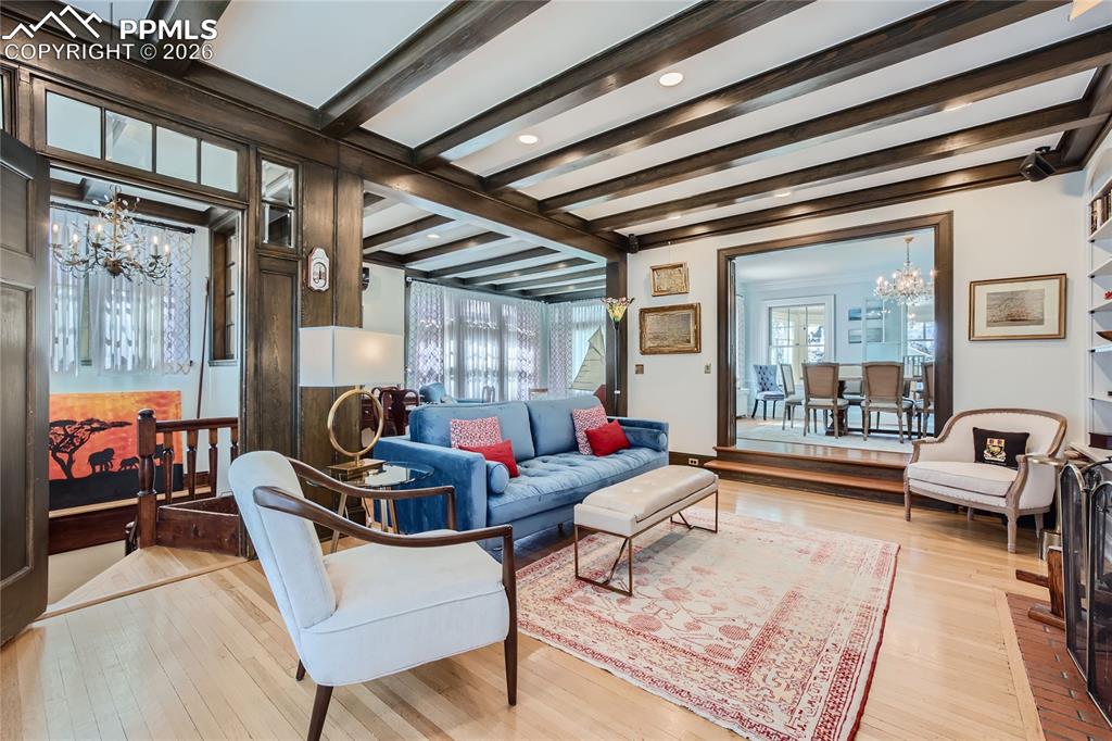 Living room featuring an inviting chandelier, beamed ceiling, and light hardwood / wood-style flooring
