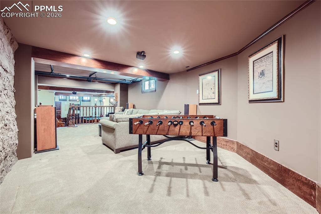 Recreation room featuring crown molding, beamed ceiling, a wealth of natural light, and light colored carpet