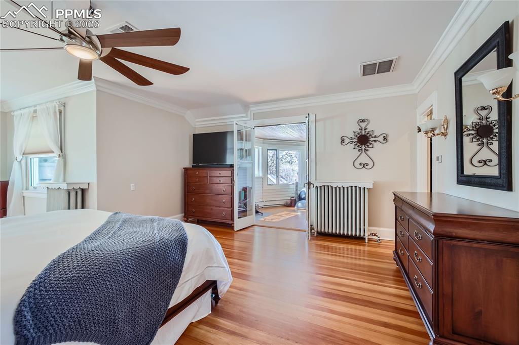 Bedroom with ornamental molding, radiator, light wood flooring, and ceiling fan