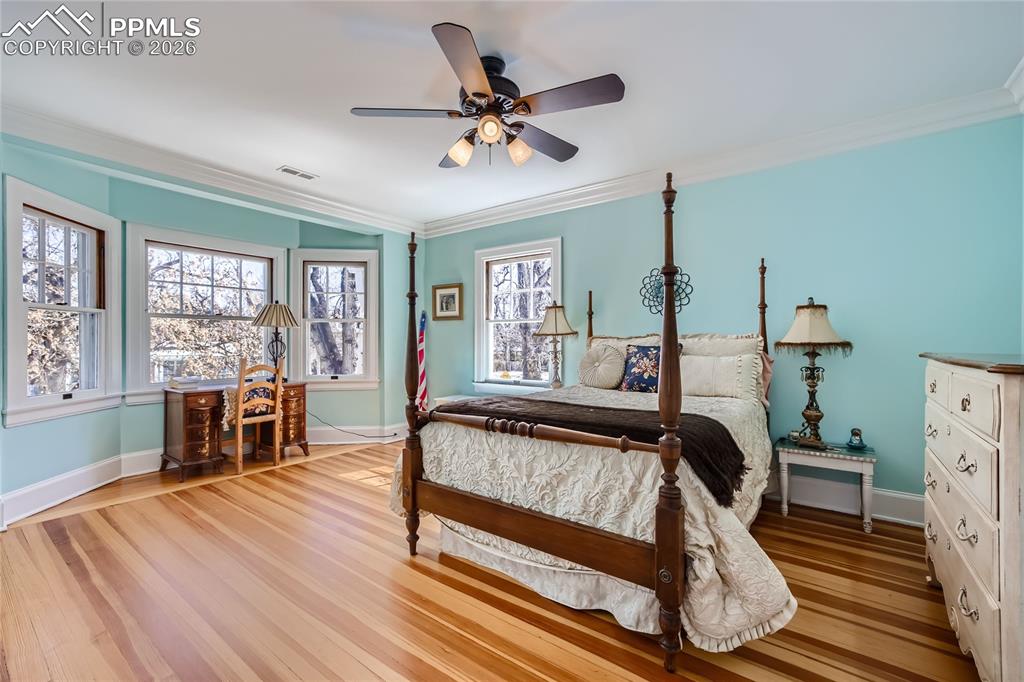 Bedroom featuring ceiling fan, ornamental molding, and light hardwood flooring