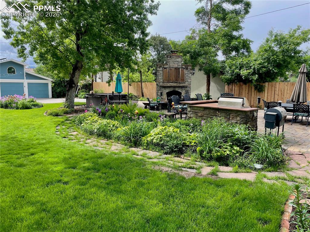 View of yard featuring a patio area, an outdoor stone fireplace, and a garage