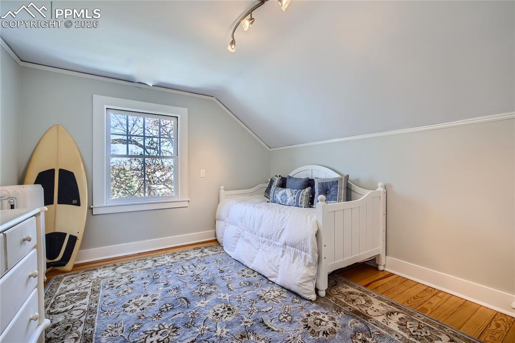 Bedroom with lofted ceiling, track lighting, and light wood flooring