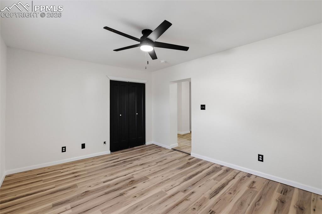 Unfurnished bedroom with light wood-style flooring, ceiling fan, and a closet