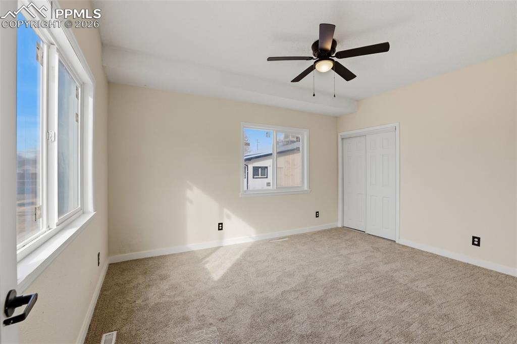 Unfurnished bedroom featuring light colored carpet, a closet, and ceiling fan