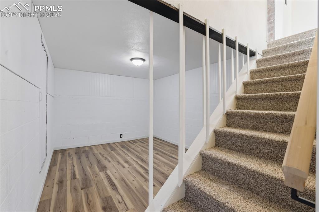 Stairs featuring concrete block wall and wood finished floors