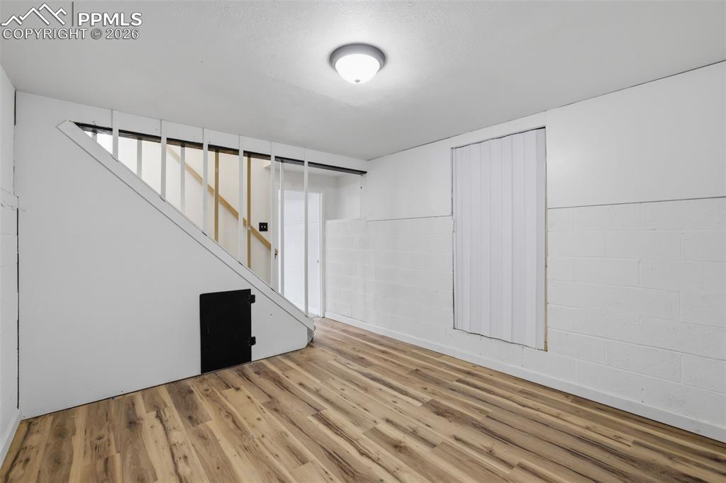 Finished basement featuring concrete block wall and wood finished floors