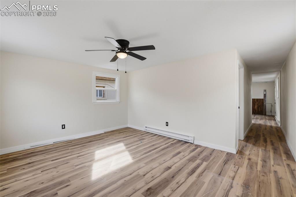 Unfurnished room with a baseboard heating unit, light wood finished floors, and a ceiling fan
