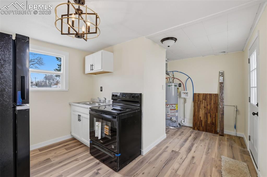 Kitchen with white cabinets, black appliances, light countertops, and light wood finished floors