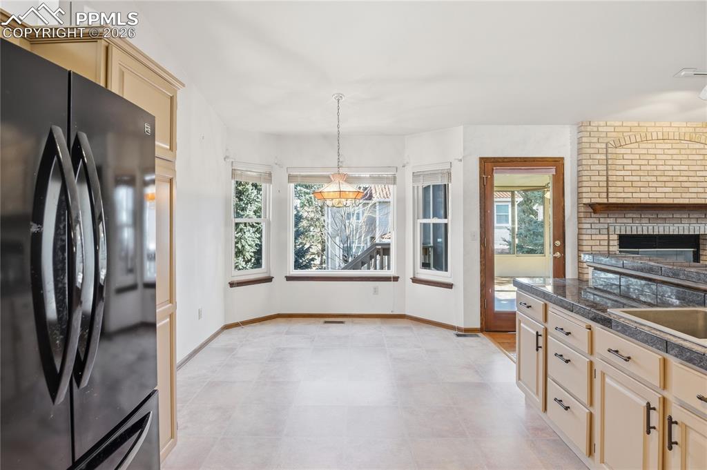 Kitchen with freestanding refrigerator, light brown cabinetry, healthy amount of natural light, and decorative light fixtures