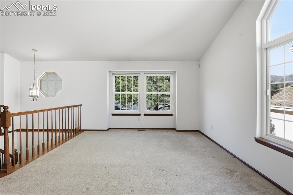 Unfurnished room featuring healthy amount of natural light, light carpet, and lofted ceiling