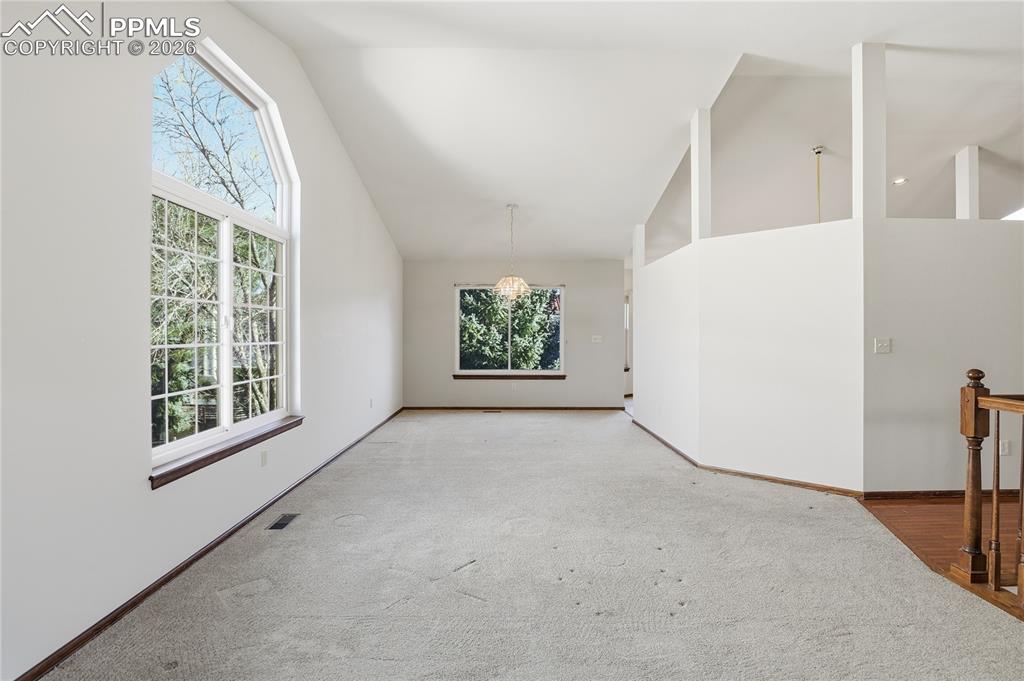 Empty room featuring high vaulted ceiling and carpet flooring