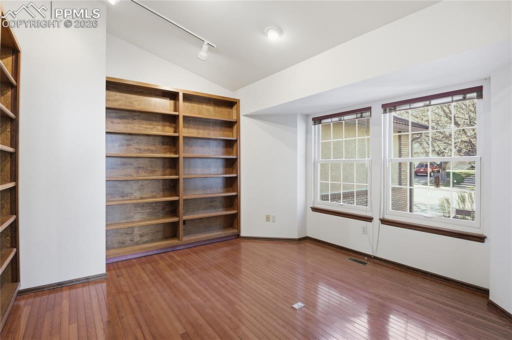 Unfurnished room with vaulted ceiling, hardwood / wood-style floors, and rail lighting