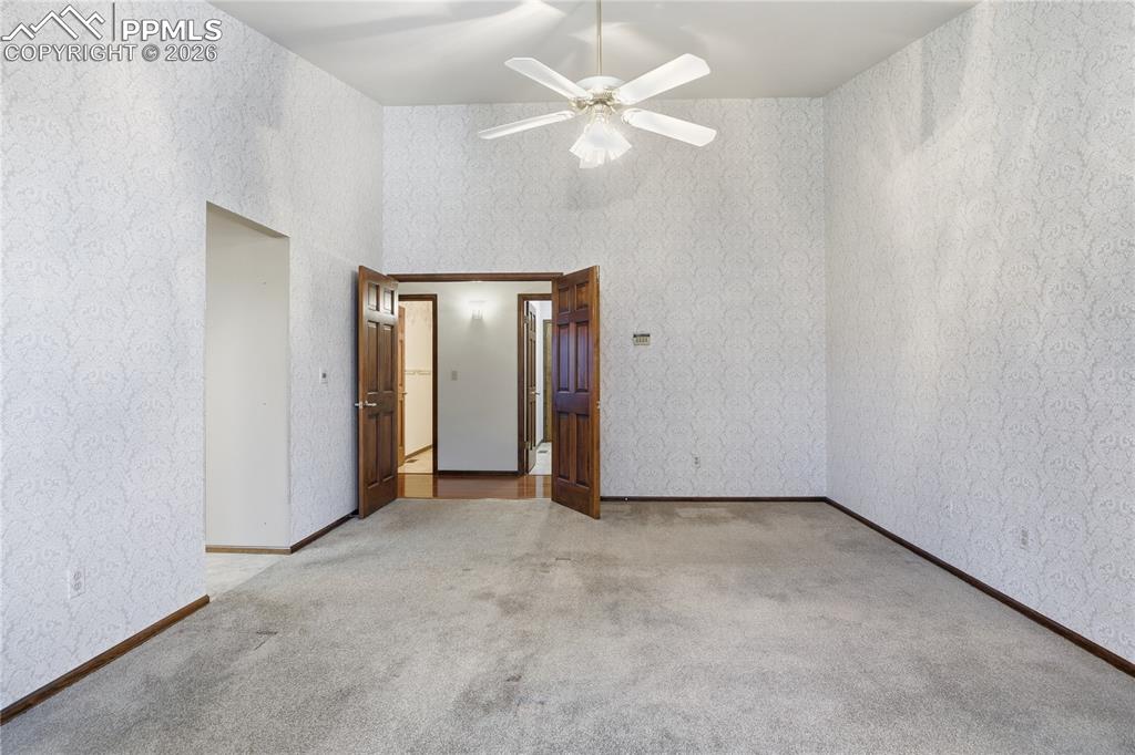 Unfurnished bedroom with wallpapered walls, light carpet, and ceiling fan