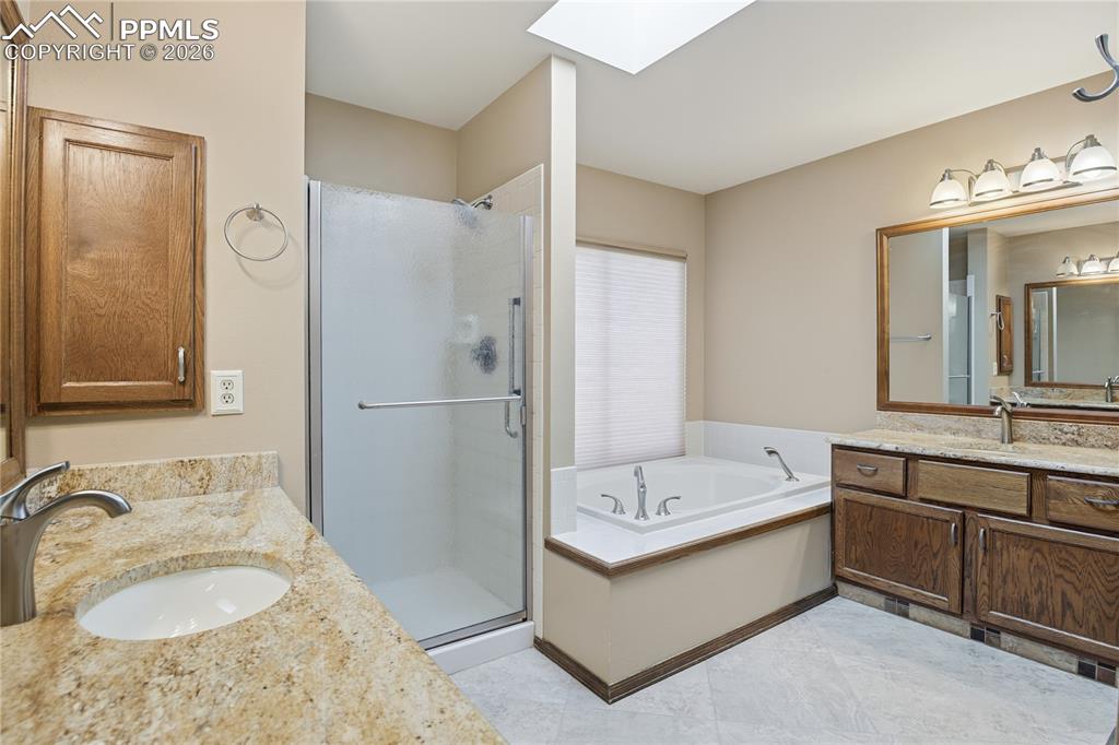 Bathroom with a skylight, two vanities, a bath, and a shower stall