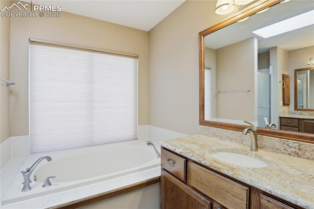 Bathroom featuring vanity, a garden tub, and a skylight