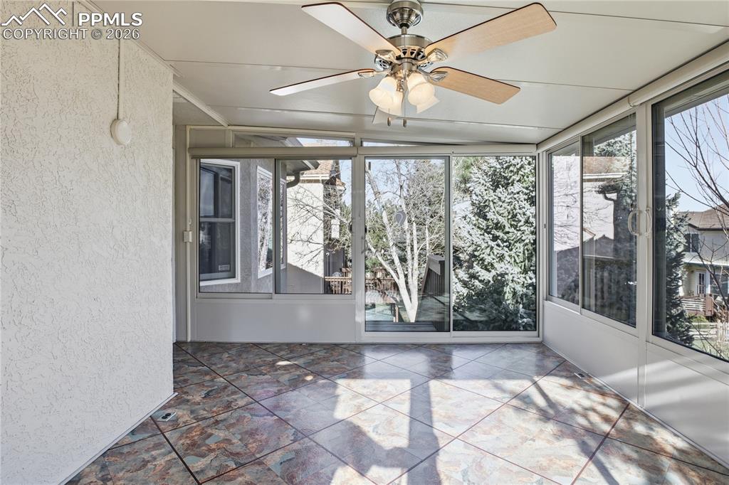 Unfurnished sunroom with ceiling fan and plenty of natural light