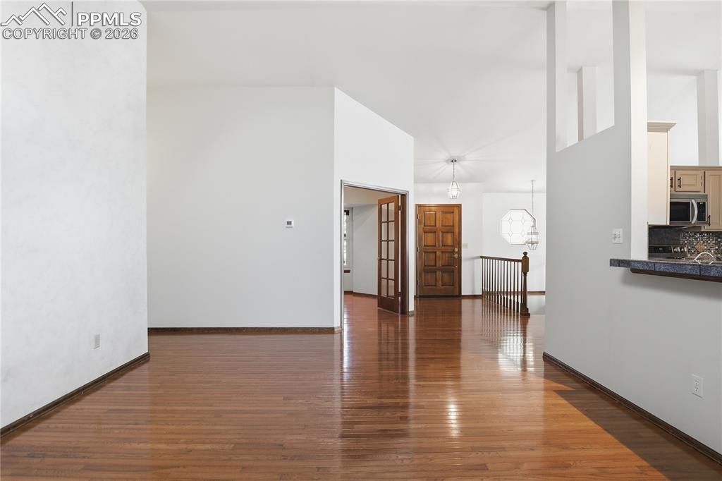 Unfurnished living room featuring dark wood finished floors, high vaulted ceiling, french doors, and a chandelier