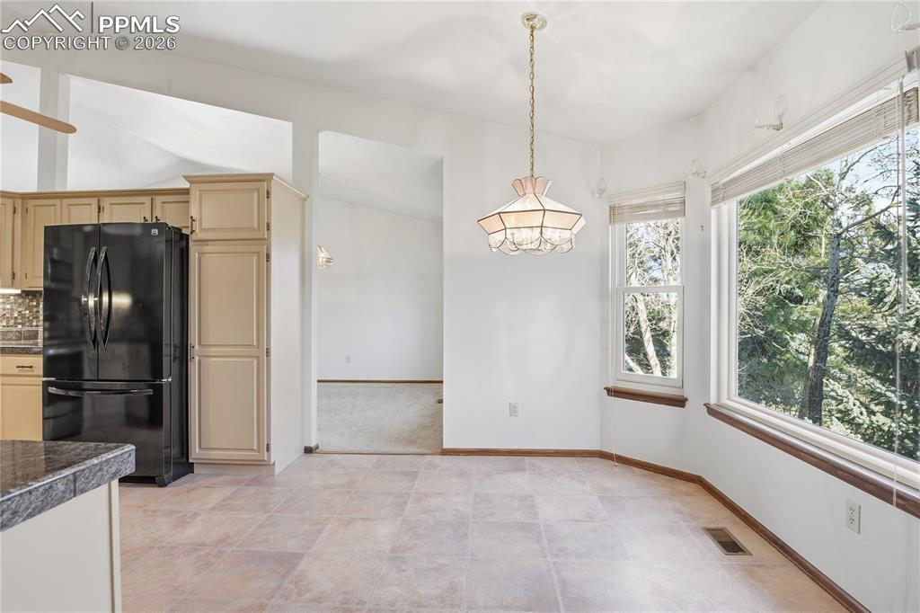 Kitchen featuring freestanding refrigerator, decorative light fixtures, tasteful backsplash, and tile countertops