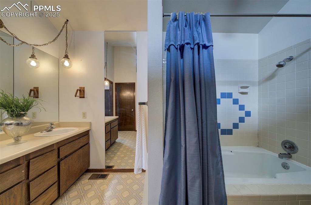 Primary Bathroom with extended vanity, mirror, and tiled tub/shower.
