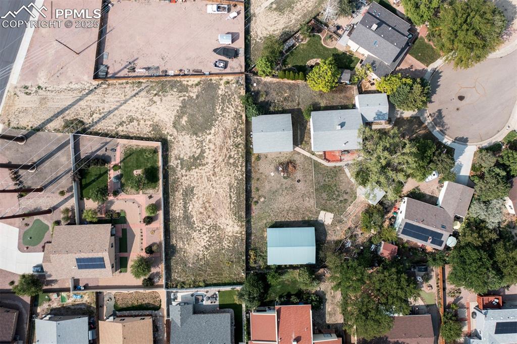 Aerial rear view of home, 3-car detached garage, and adjacent 0.44-acre vacant lot included in sale.