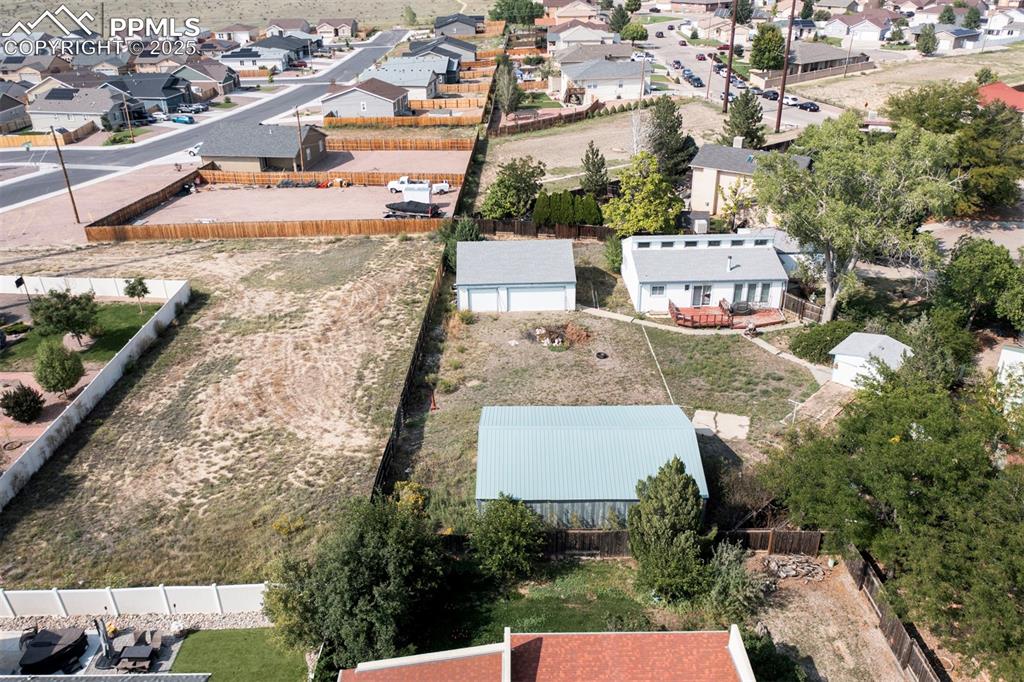 Aerial rear view of home, 3-car detached garage, and adjacent 0.44-acre vacant lot included in sale.