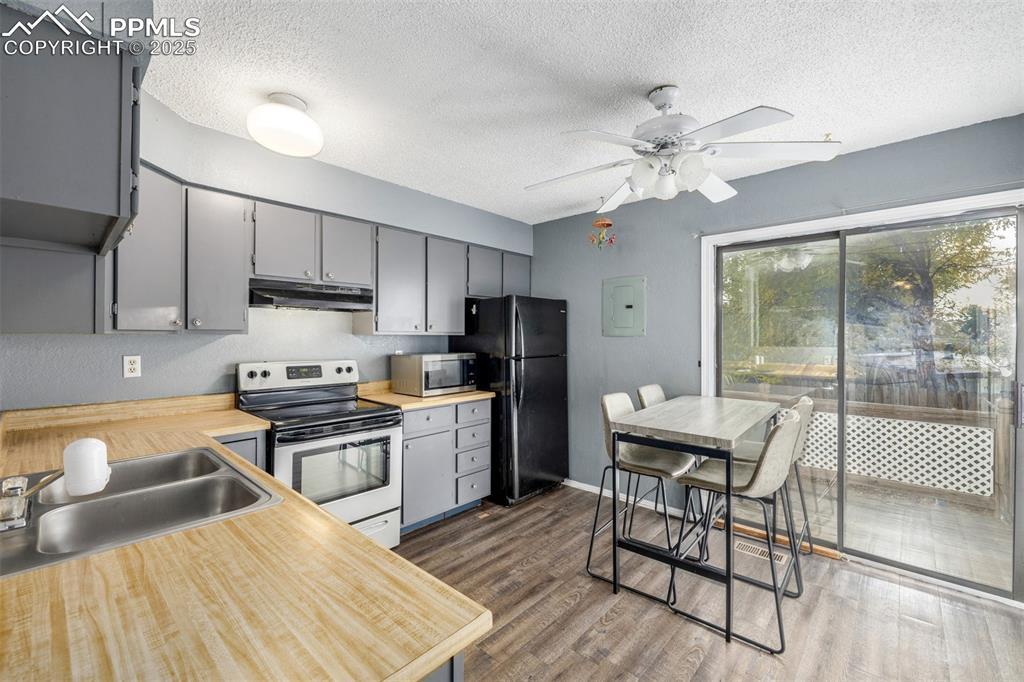 Kitchen featuring gray cabinetry, electric range oven, light countertops, dark wood-style flooring, and a textured ceiling