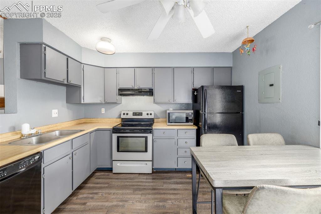 Kitchen featuring black appliances, gray cabinetry, light countertops, dark wood-style flooring, and a textured ceiling