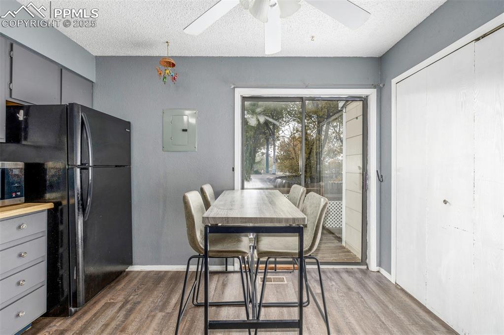 Dining area featuring a textured ceiling, electric panel, dark wood-style floors, and a ceiling fan