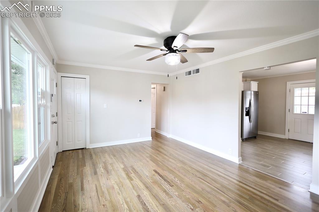 Spare room with ornamental molding, light wood-style floors, and a ceiling fan