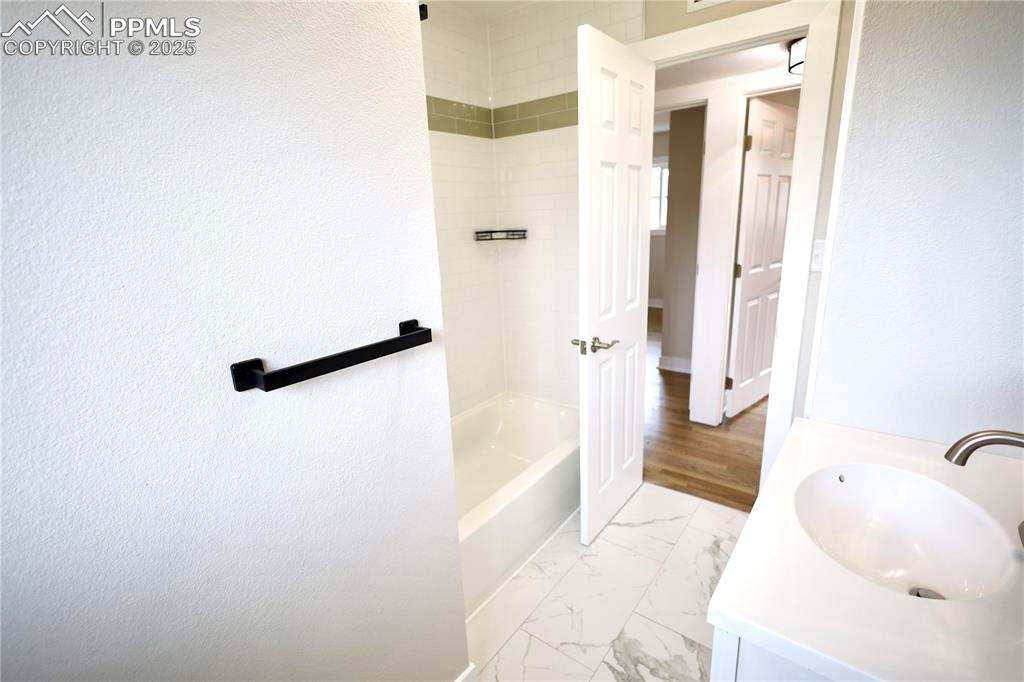 Full bathroom featuring vanity, bathing tub / shower combination, and light marble finish floors