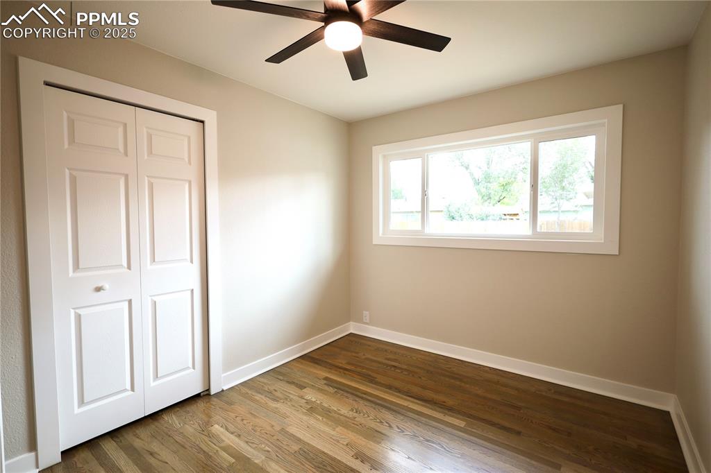Unfurnished bedroom featuring dark wood finished floors, a closet, and ceiling fan