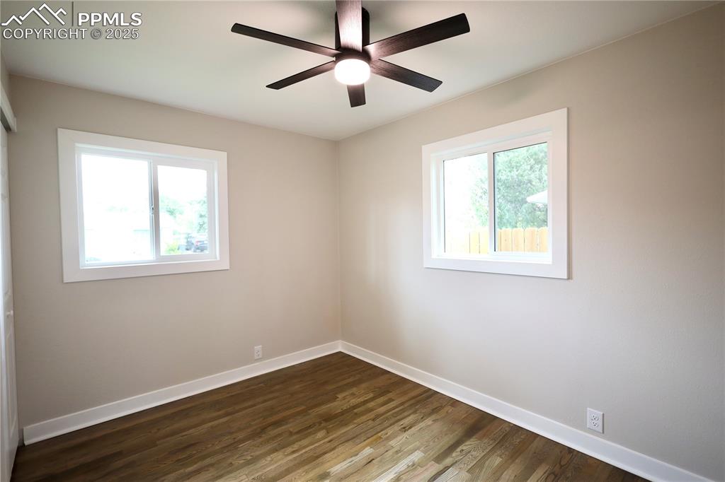 Unfurnished room with dark wood-style floors and a ceiling fan