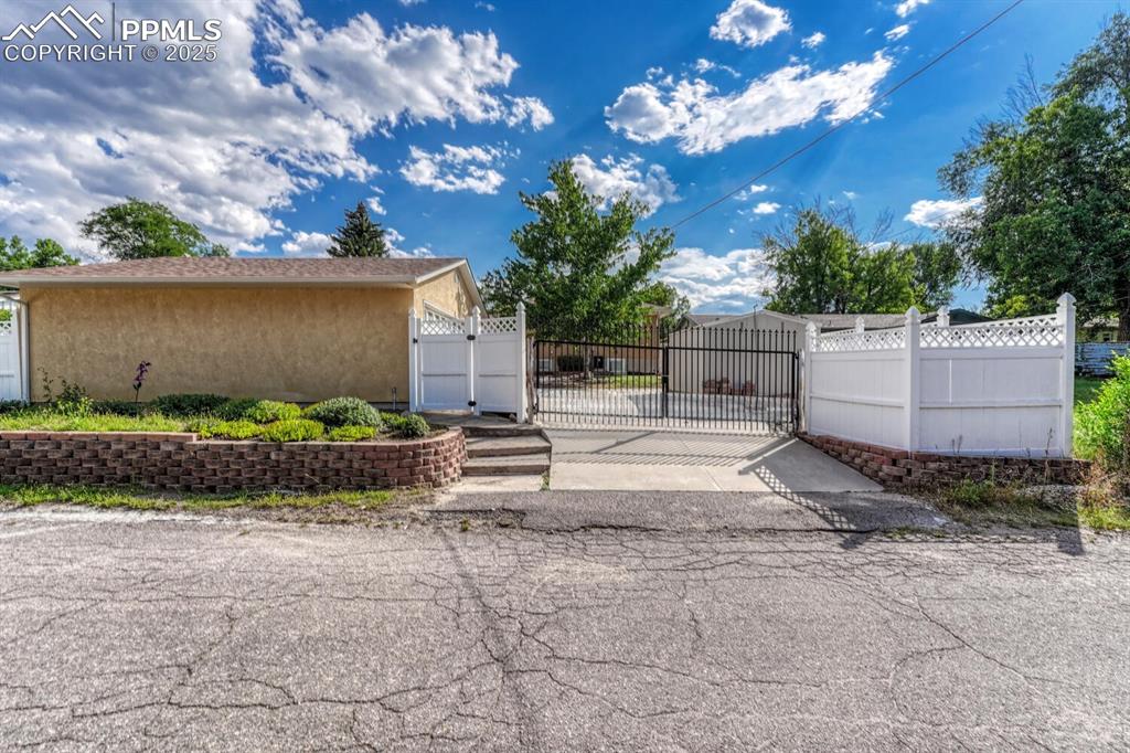 View from alley showing gate, detached garage, and shed