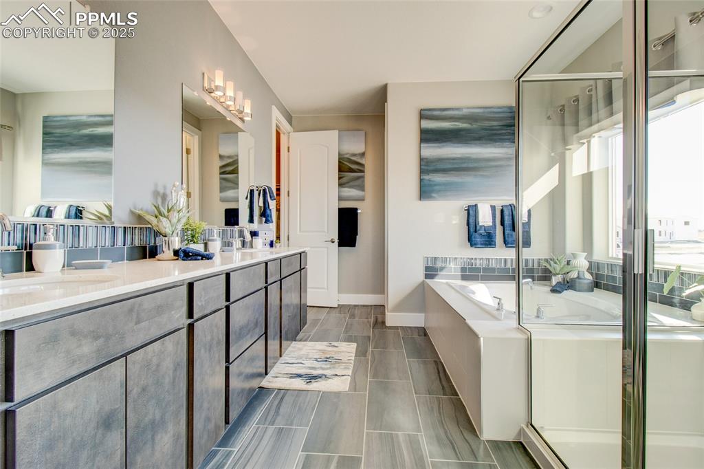 Bathroom featuring double vanity, a garden tub, and a stall shower