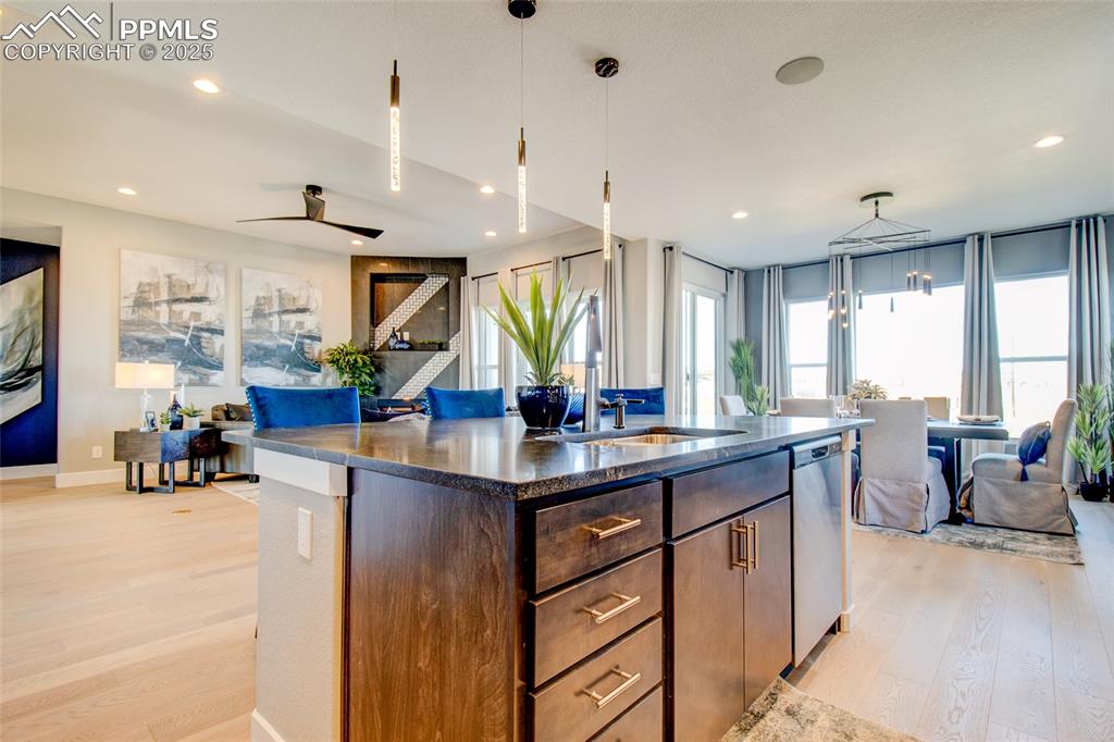 Kitchen featuring open floor plan, light wood-type flooring, a center island with sink, decorative light fixtures, and recessed lighting