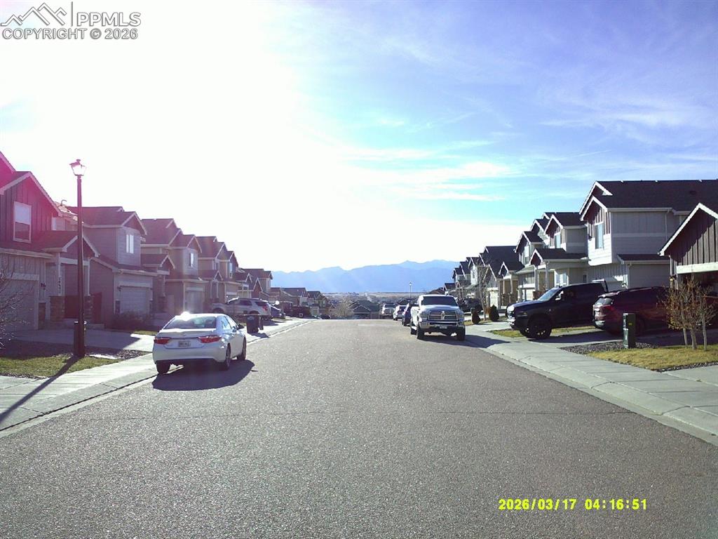 View of asphalt street with sidewalks, a residential view, curbs, and a mountain view