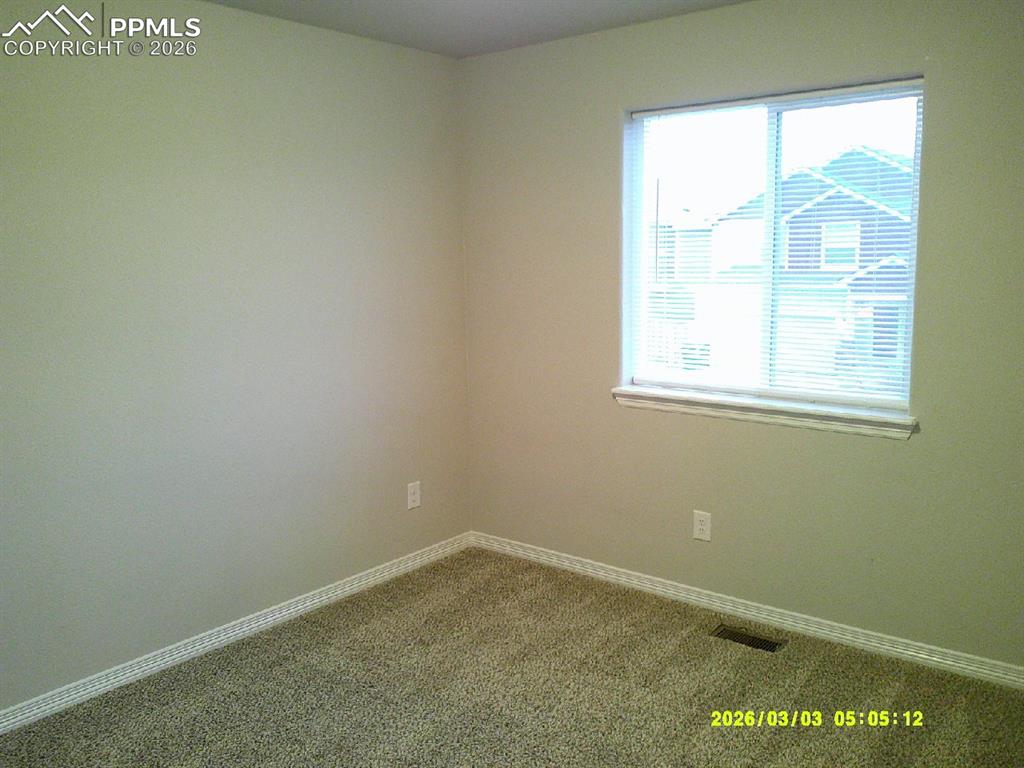Carpeted spare room featuring baseboards
