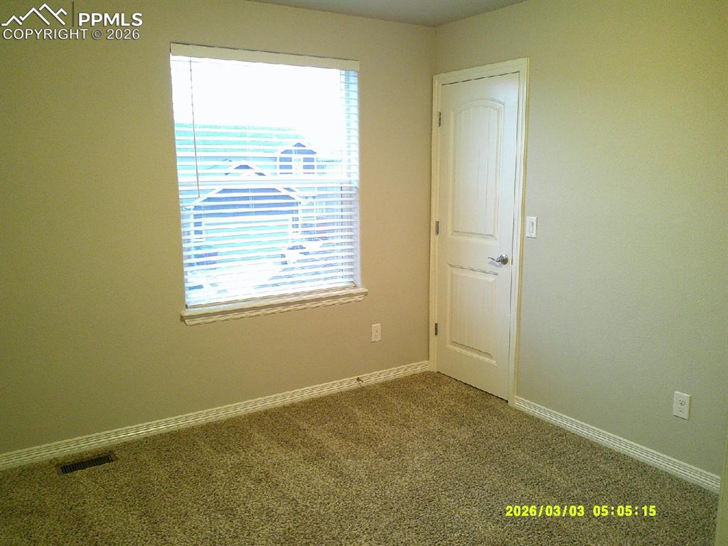Empty room featuring dark colored carpet and baseboards