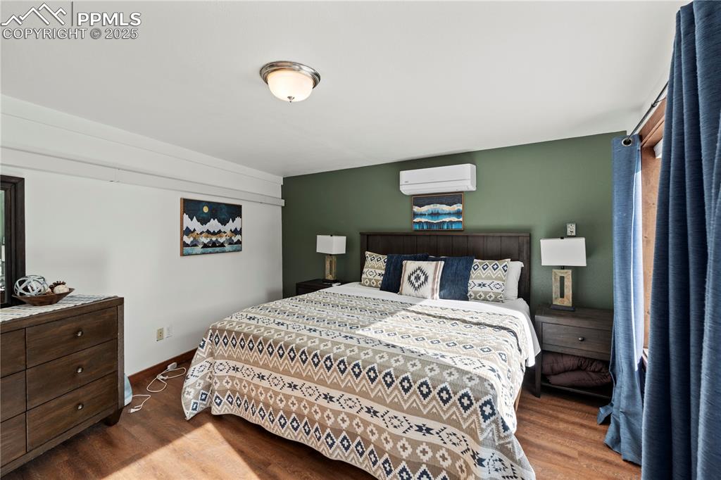 Bedroom featuring a wall unit AC and wood finished floors