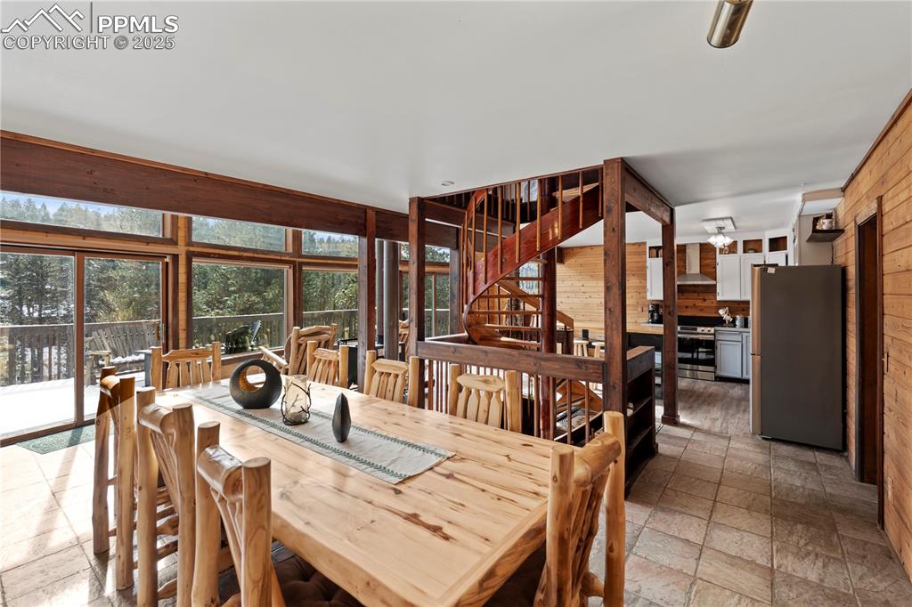 Dining space featuring wood walls, stone tile floors, and stairs