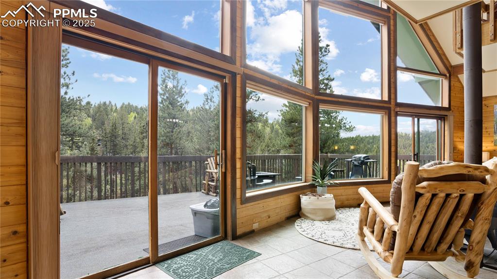Sunroom / solarium with wood walls, healthy amount of natural light, and a towering ceiling