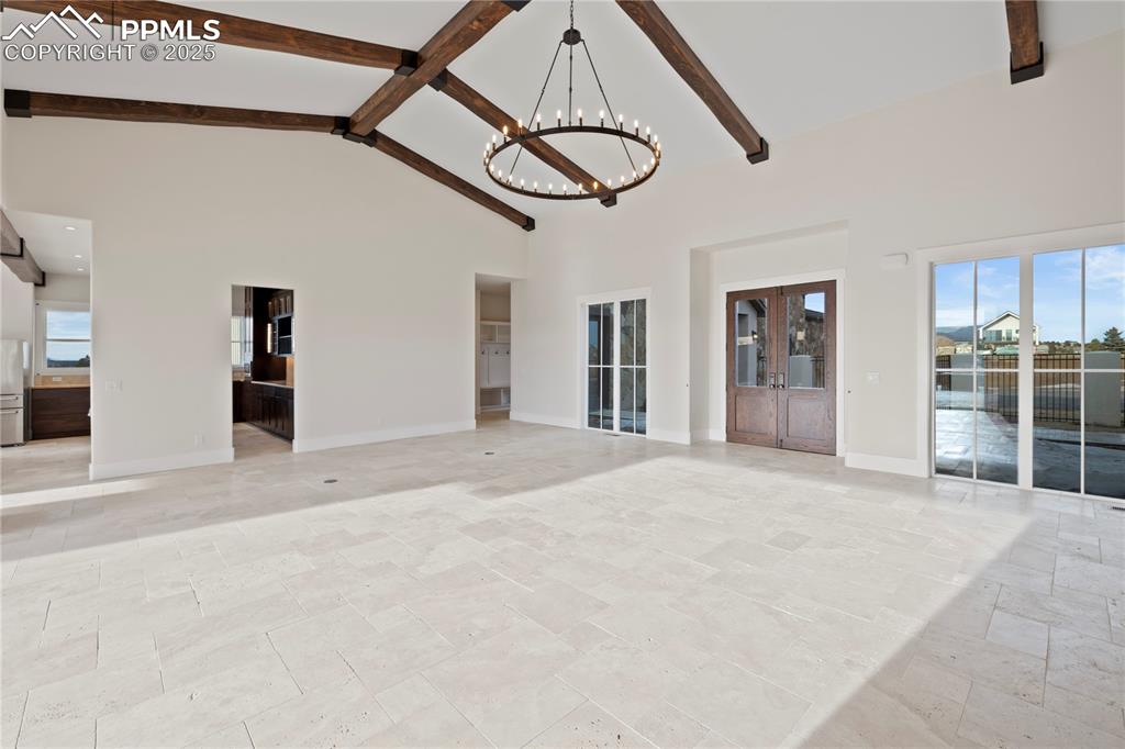 Spare room with high vaulted ceiling, a chandelier, beamed ceiling, and plenty of natural light