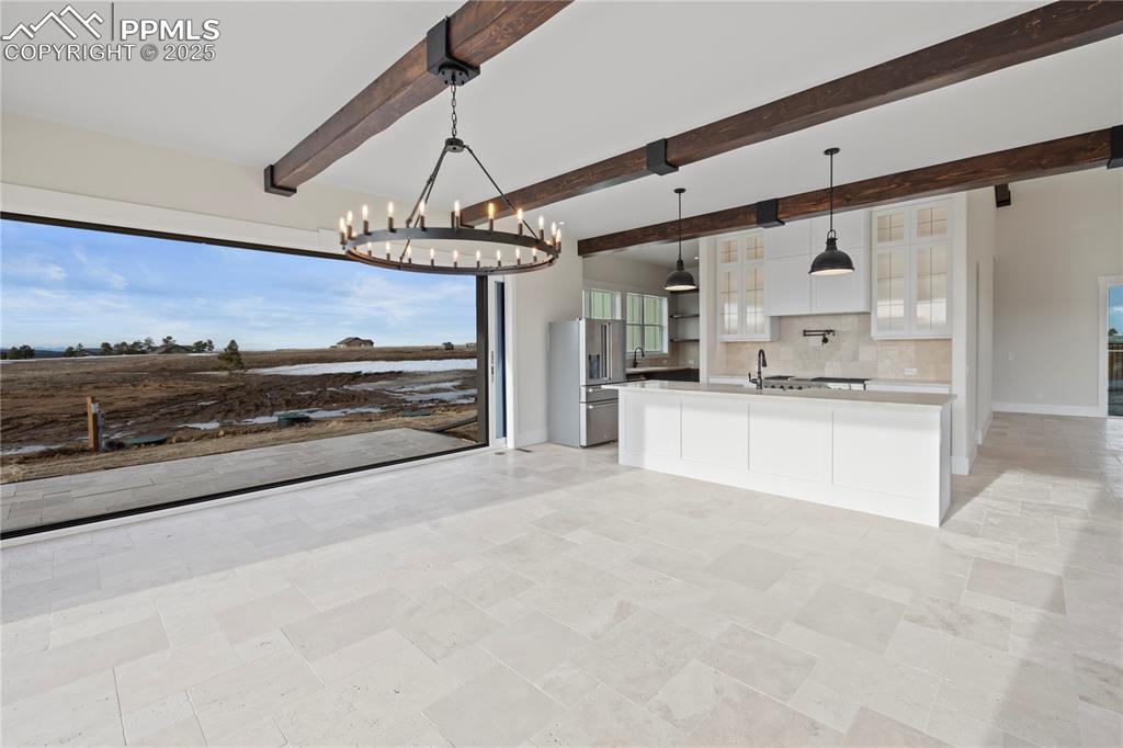 Kitchen with a notable chandelier, light countertops, stainless steel fridge with ice dispenser, white cabinets, and decorative backsplash