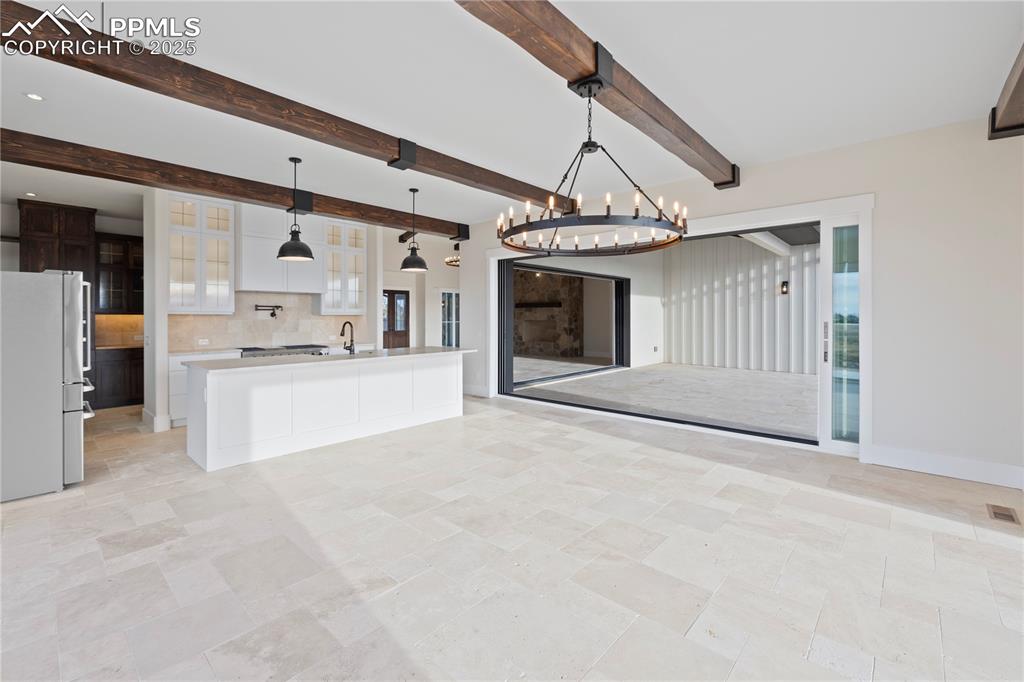 Kitchen featuring a notable chandelier, light countertops, freestanding refrigerator, white cabinetry, and decorative backsplash