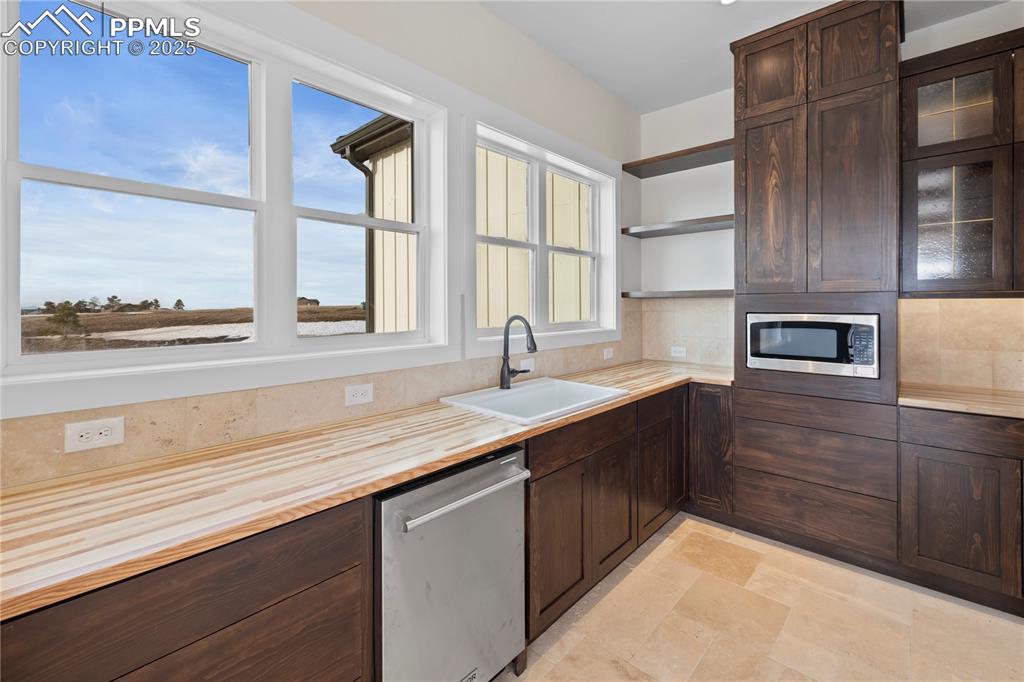 Kitchen featuring wooden counters, a sink, dark brown cabinetry, and appliances with stainless steel finishes