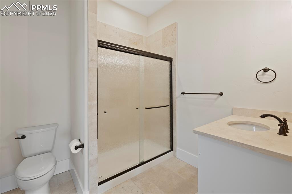 Full bath with toilet, vanity, a stall shower, and tile patterned flooring